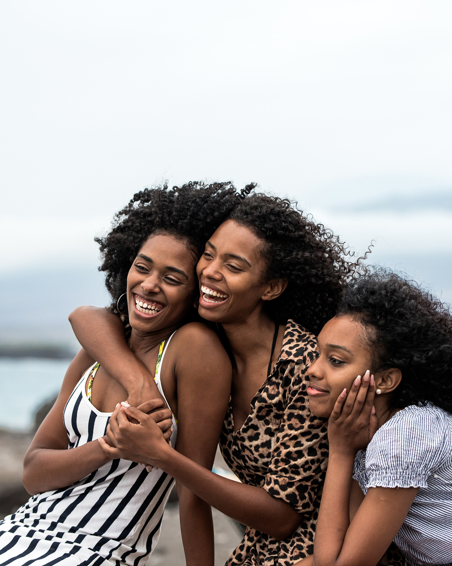 Three young black women hugging on the beach