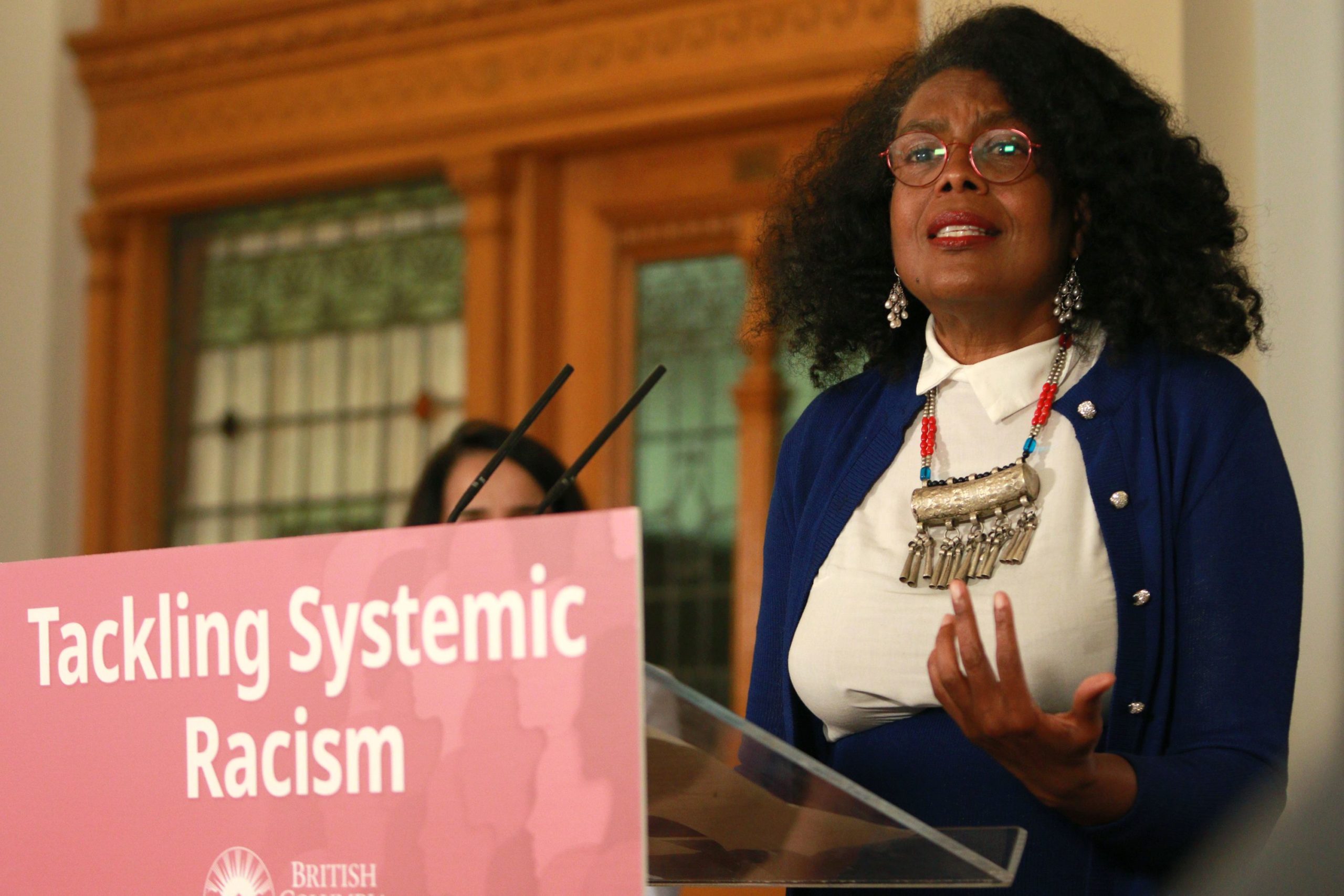 Dr. June Francis, co-director, The Co-Laboratorio Project; director, Institute for Diaspora Research and Engagement; associate professor, Beedie School of Business SFU; chair, Hogan's Alley Society, speaking at a podium during a press conference at the introduction of BC’s Anti Racism Data Act.