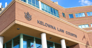 Exterior of Kelowna Law Courts, with courthouse signage and provincial crest.